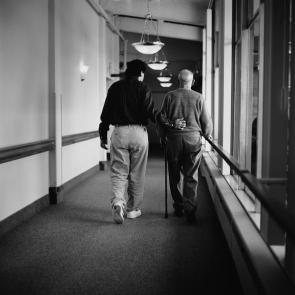 b & w photo of man helping elderly man walk down hallway RDS Environmental Colorado